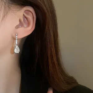 Close-up detail of elegant silver water drop earrings with sparkling rhinestones on model