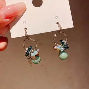 Close-up of bohemian drop earrings featuring green glass beads and sparkling zircon