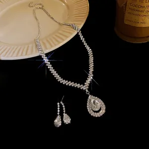 Detailed view of rhinestone-encrusted water-drop necklace and earring set on reflective surface