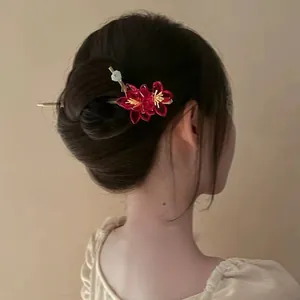 Detailed view of an elegant red flower hair stick accessory worn on a stylish bun