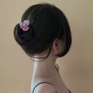 Elegant pink flower hair fork detail in a bun, showcasing a delicate fairy style accessory.