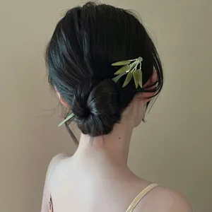 Elegant back view of a woman wearing a green bamboo leaf hair stick in a sleek bun.