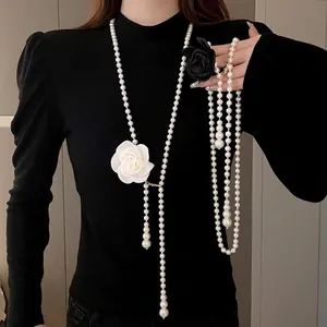 Elegant long pearl sweater chain necklace featuring white and black camellia flower accents