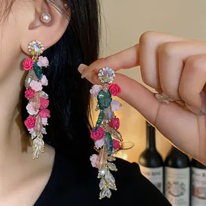 Close-up detail of luxury crystal tassel earrings with elegant pink and fuchsia resin roses.