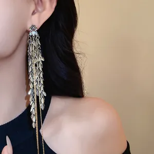 Detailaufnahme langer Quastenohrringe mit Weizenähren-Design am Ohr des Models