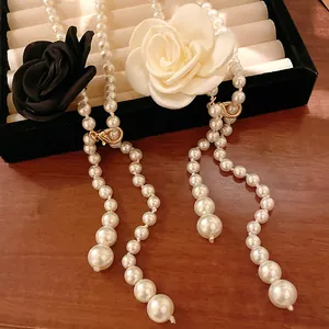 Close-up of vintage pearl sweater chain with black and white fabric rose accents.