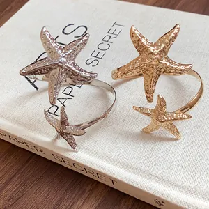 Close-up detail of silver and gold starfish arm cuffs on a textured book cover