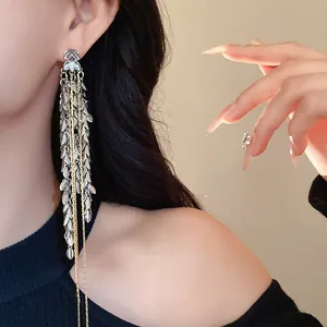 Elegante lange Quasten-Ohrringe mit silbernen und goldenen Blättern in Nahaufnahme