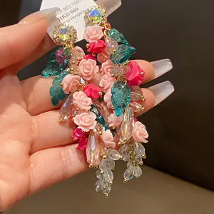 Detailed close-up of luxury floral tassel earrings with sparkling crystals and pink roses
