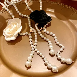 Detailed view of retro pearl necklace with black and white fabric roses on gold tray