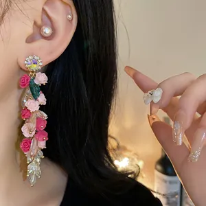 Macro view of elegant long floral tassel earrings featuring pink roses and crystals
