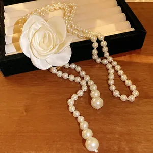 Elegant vintage long pearl necklace featuring a large white fabric camellia flower detail
