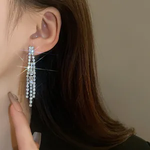 Close-up of elegant silver tassel earrings with sparkling rhinestones on model.