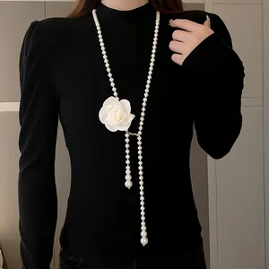 Long pearl necklace with white rose flower pendant on black sweater