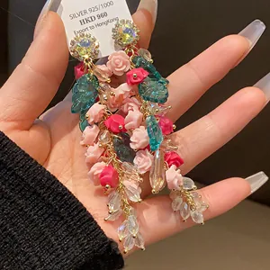 Detail view of heavy floral crystal tassel earrings with pink roses and clear beads.