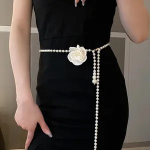 Detail view of an elegant long pearl necklace with white flower on a black dress