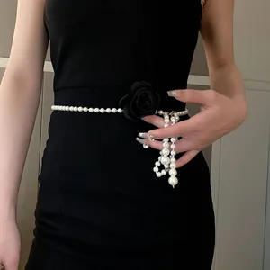 Close-up of retro pearl necklace with black flower worn as an elegant waist chain.