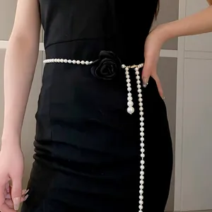 Detail shot of a long pearl waist chain with a black fabric rose flower ornament.