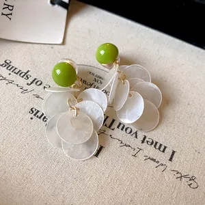 Macro detail of the fresh green bead and delicate white shell tassels on these earrings