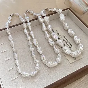 Elegant French minimalist irregular baroque pearl beaded necklace displayed in a wooden tray