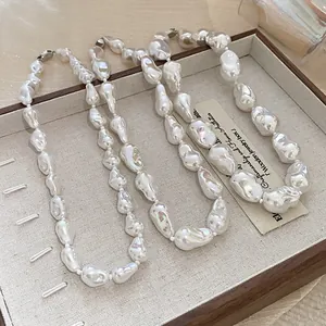 Close-up of irregular baroque pearl necklaces displayed in a wooden jewelry tray.