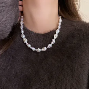 Elegant irregular baroque pearl necklace styled on a soft dark brown knit sweater.