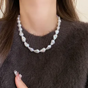 Elegant close-up of irregular baroque pearl choker necklace on a fuzzy brown sweater.