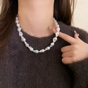 Detail view of a minimalist irregular baroque pearl choker necklace worn by a model