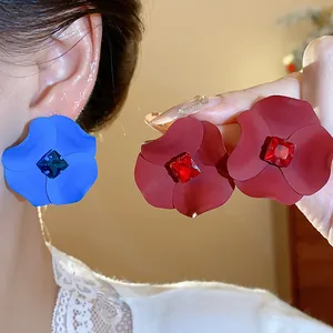 Close-up detail of oversized spray-painted flower earrings with inlaid rhinestones
