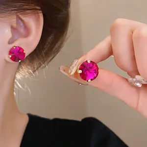 Detailed view of luxury fuchsia round crystal stud earrings with gold claw setting on ear