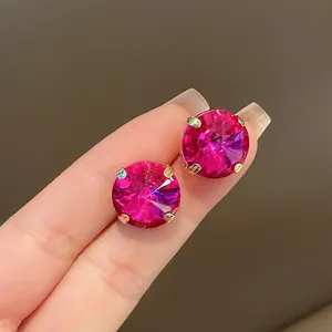 Detailed view of elegant round pink crystal stud earrings with gold claw setting on fingers