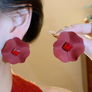 Detail shot of matte dark red spray-painted flower stud earrings with a red crystal center.