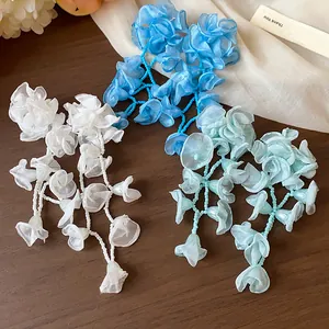 Close-up detail of romantic chiffon flower tassel earrings in white, blue and light cyan colors