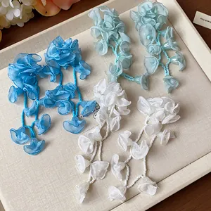 Detailed macro view of handmade chiffon flower tassel earrings in three vibrant colors