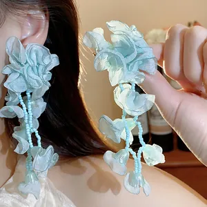 Close-up detail of light blue chiffon flower earrings with delicate beaded tassels