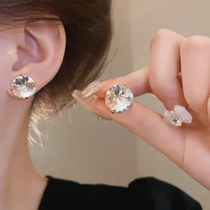 Detail of large sparkling round crystal stud earrings with elegant gold claw setting