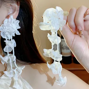 Close-up of elegant white chiffon flower tassel earrings for a sweet holiday look