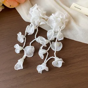 Close-up of elegant white chiffon flower tassel earrings with intricate bead details