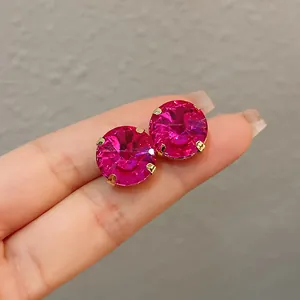 Close-up view of vibrant pink faceted crystal stud earrings in a polished gold setting