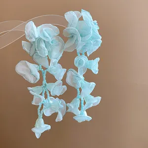 Detailed macro view of light blue chiffon flower fringe earrings with delicate bead accents