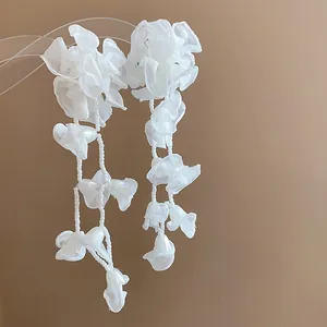 Detail of elegant white chiffon flower tassel earrings with delicate pearl bead strands.