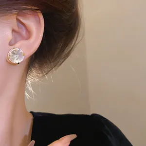 Detailed view of a large clear round faceted crystal stud earring worn elegantly on a model's ear
