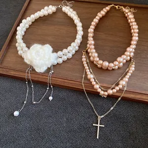 Close-up of double-layer white pearl necklace with flower and pink pearl cross necklace