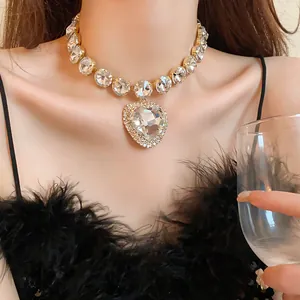 Close-up of heavy heart rhinestone necklace on a model wearing a black feather dress.