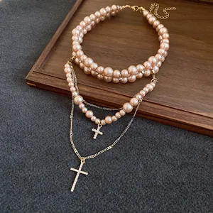 Detail shot of an elegant double-layered champagne pearl necklace with cross pendants