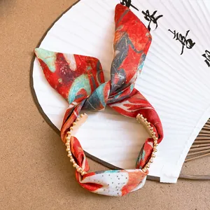 Detailed view of an ethnic style gold cuff bracelet with red floral fabric bow.