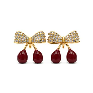 Boucles d'oreilles nœud cerise plaquées or avec zircone et détails en émail rouge