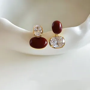 Dettaglio ravvicinato di orecchini asimmetrici con perline rosse e zirconi scintillanti