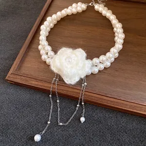 Detail of vintage double-layer pearl necklace with a handmade white knitted flower