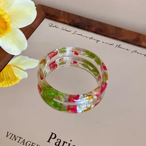Macro view of transparent acrylic bangle with colorful embedded dried flowers
